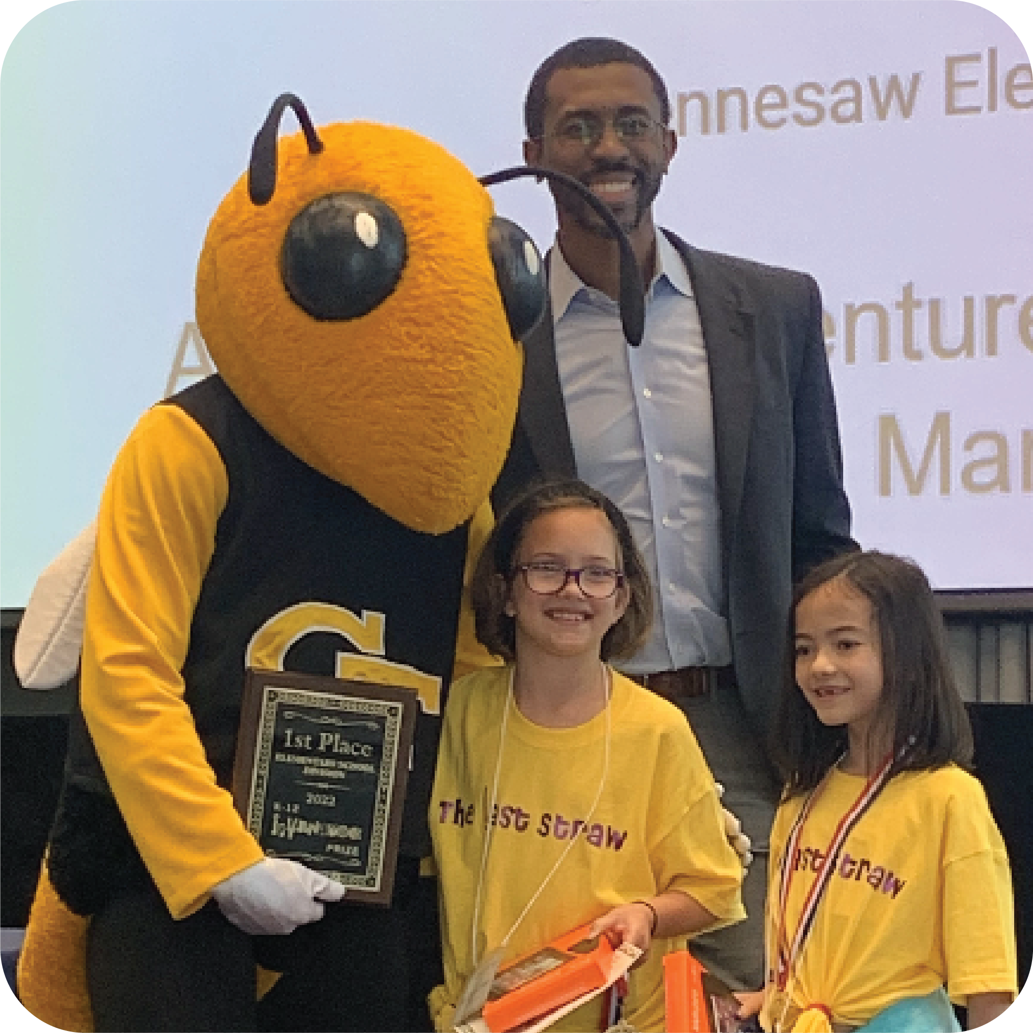 Two smiling students holding prizes and standing next to Buzz (Georgia Tech's yellowjacket mascot) holding a plaque and Craig Cupid (Georgia Intellectual Property and Alliance representative).